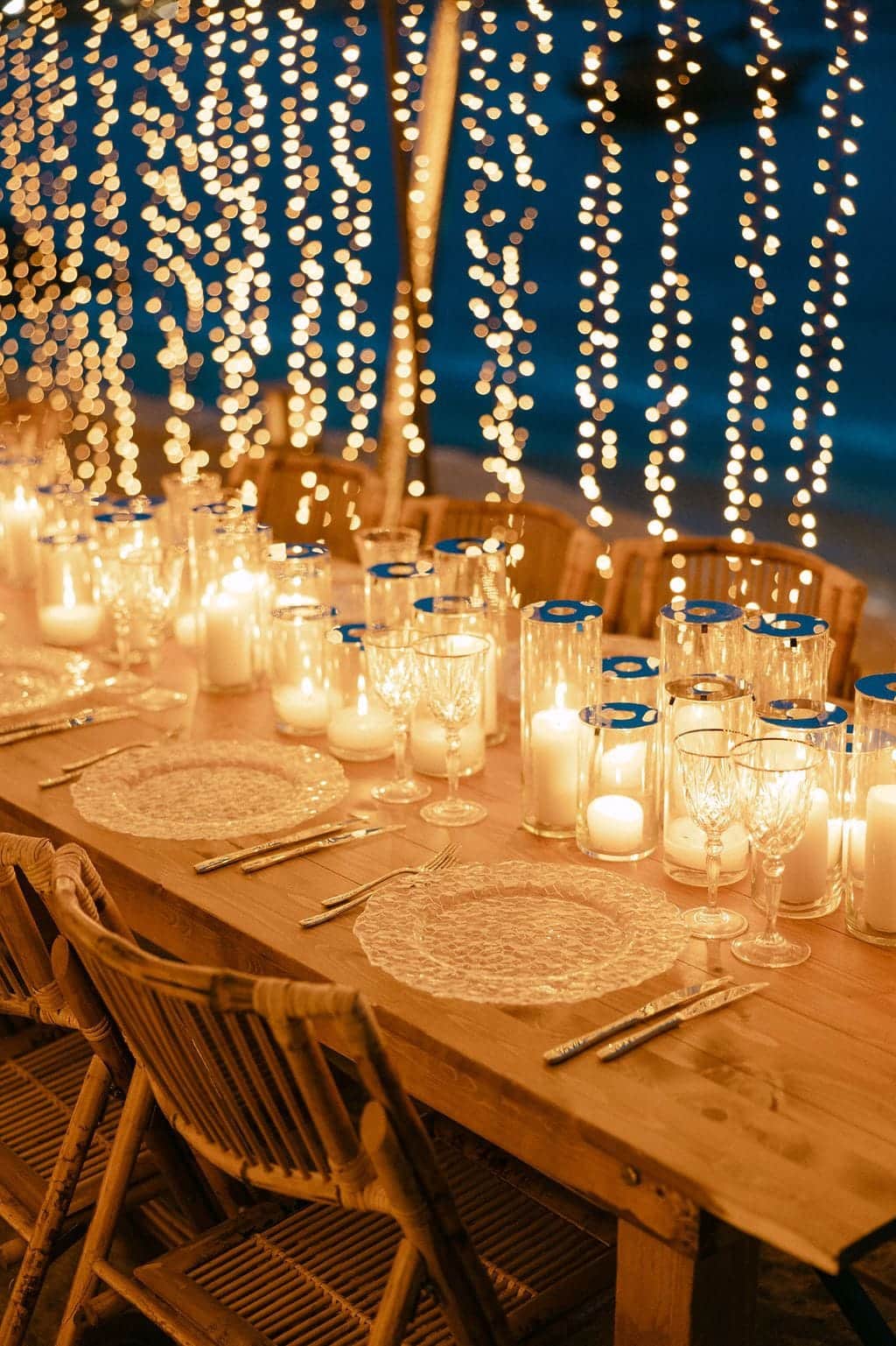 Candlelit dinner table beneath curtains of fairy lights