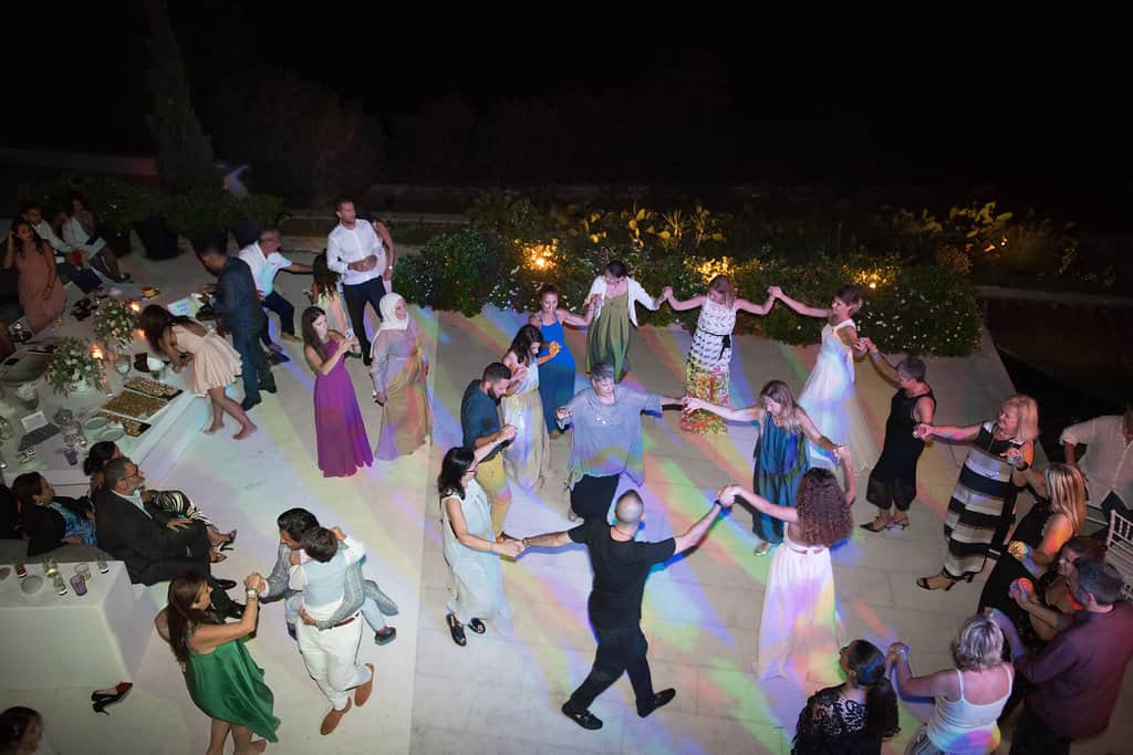 Guests in a circle dance on a villa terrace at Dimitra and Hussein's wedding on Paros