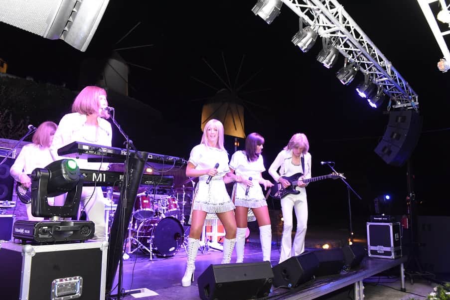 Live tribute band performing on stage under moving-head lights in Mykonos