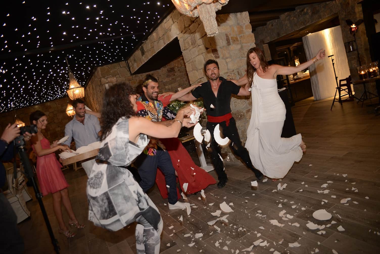 Bride dancing among smashed plates in a traditional Greek celebration at Ingrid and Hans's Mykonos wedding