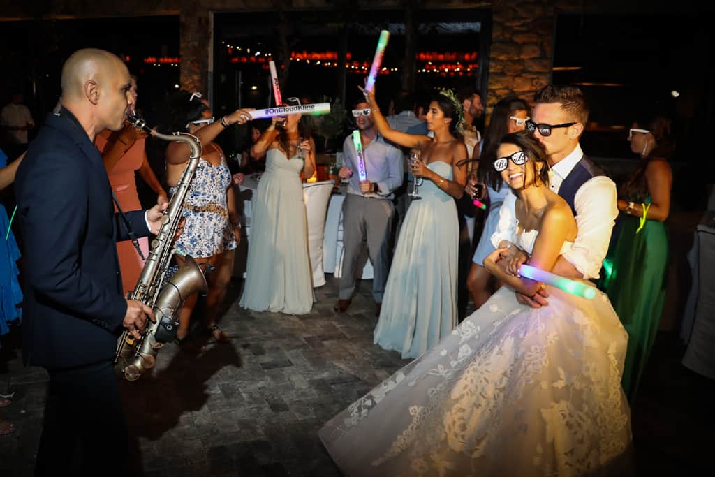 Saxophonist playing beside the bride and groom as guests wave LED foam sticks